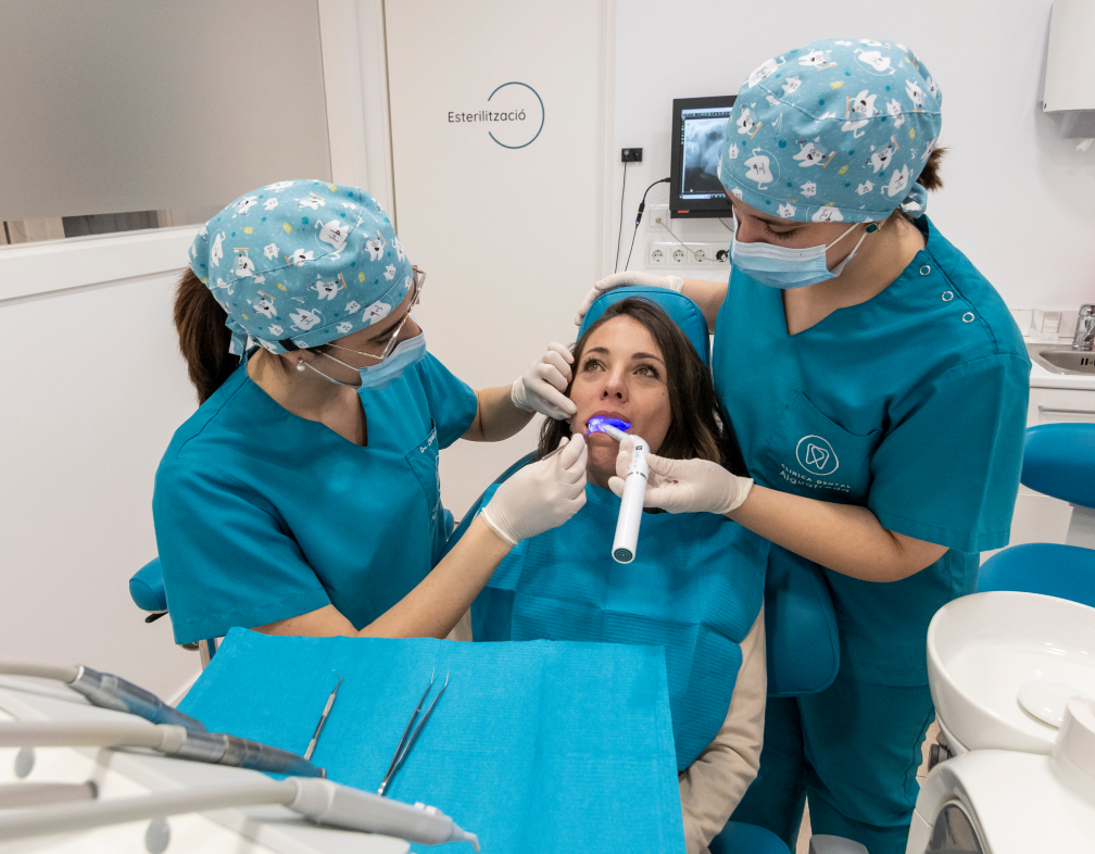 dos dentistes de la Clínica Dental Aiguafreda atenent una pacient al box